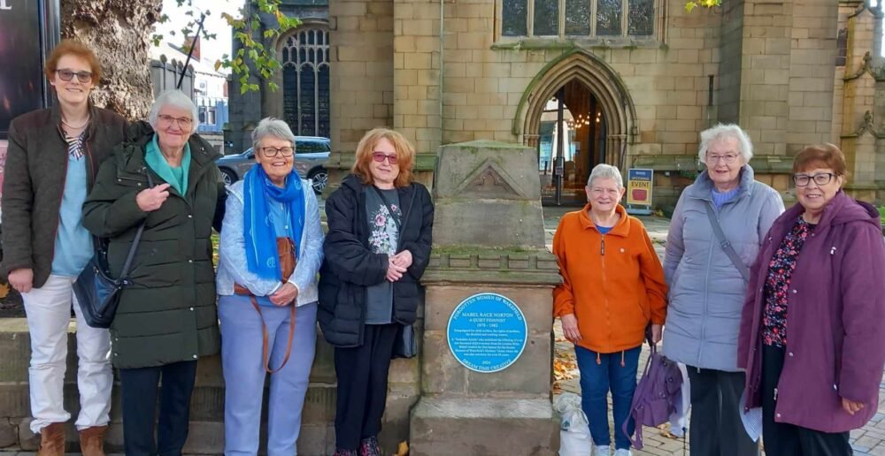 A group of Mothers' Union members with researcher Sue and Mabel Norton's blue plaque